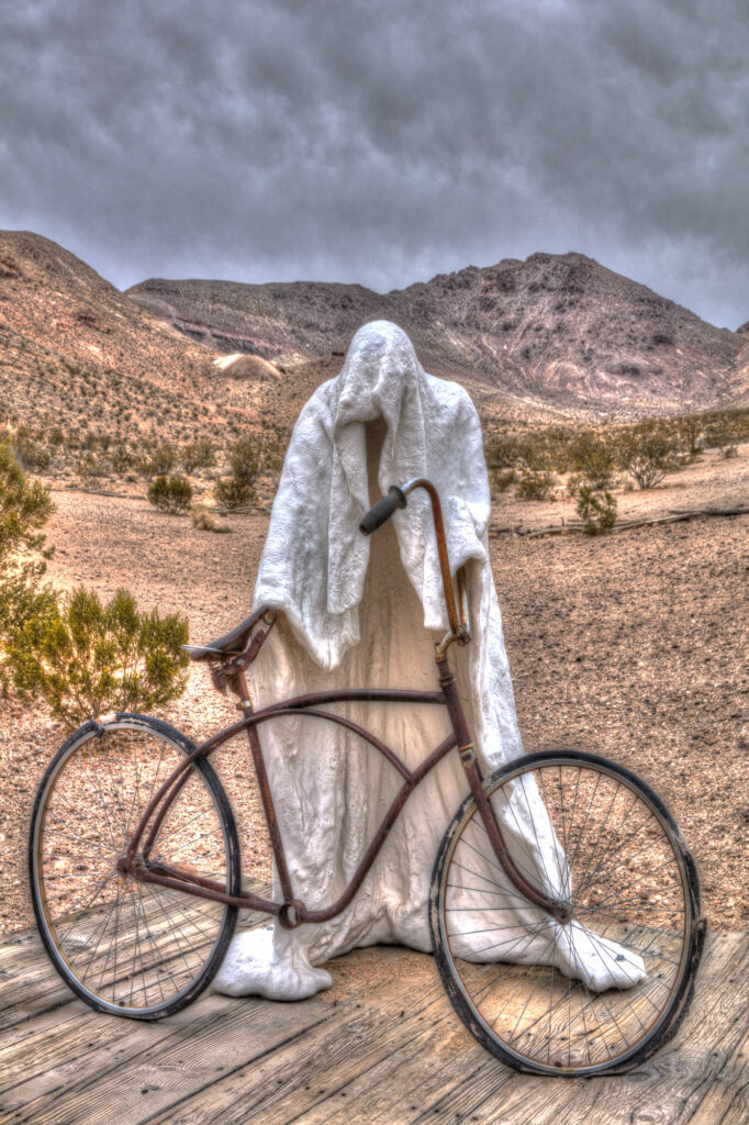 Ghostly Figure Holding A Bicycle With A Moody Sky At Rhyolite, Nevada