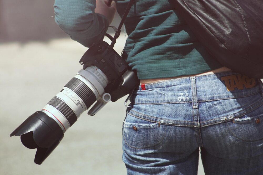 A Female Photographer With Camera On Hip